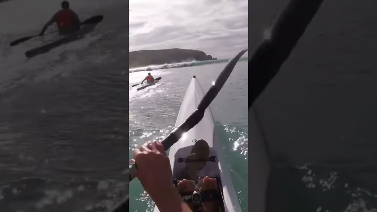 Surf ski paddling out through waves