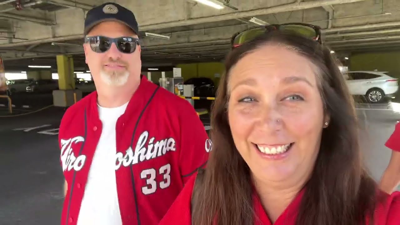 Two tourists immerse themselves in a Hiroshima Carp Baseball game at Mazda Zoom-Zoom Stadium, documenting their exhilarating experience on video.