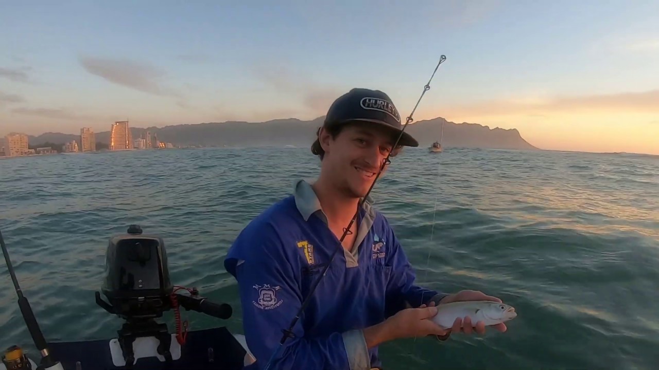 man in blue holding freshly caught fish