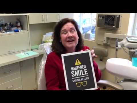 Woman in red shirt smiling after teeth whitening