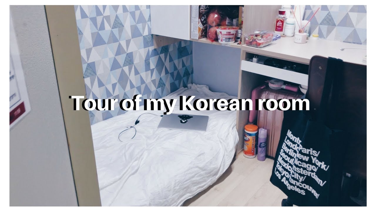 A small Korean gosiwon room with a bed shelf desk and personal items arranged efficiently in the tight micro-apartment layout