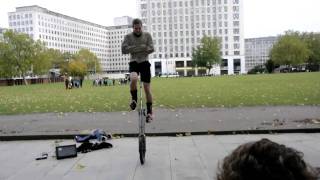 Street Performer Riding A Unicycle Wearing A Straight Jacket.AVI