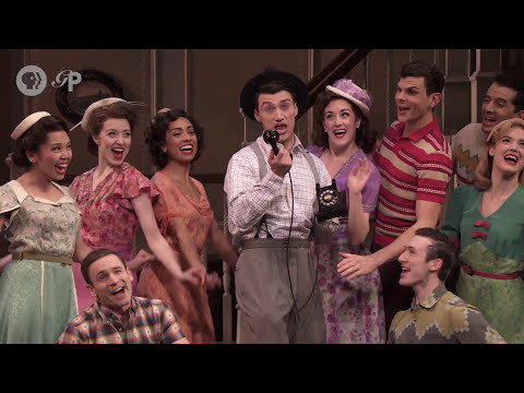 Close on the leads at a microphone, bandstand behind them as a ballad begins
