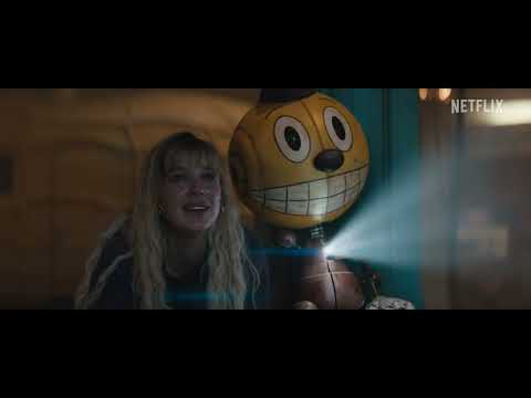 Trailer still: theme-park battleground with neon rigs and loudspeakers pumping Good Vibrations