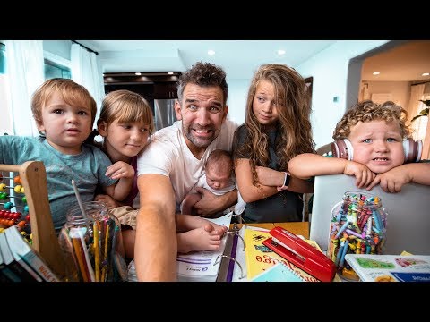 Father with five children around a cluttered table full of coloring supplies, smiling for a selfie.