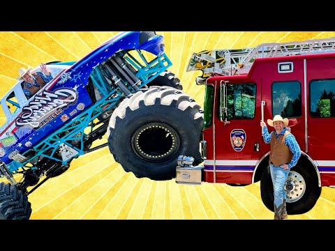 Blue monster truck tilts toward a red fire truck while a man in a cowboy hat smiles beside them against a bright yellow sunburst background, creating a playful stunt scene.