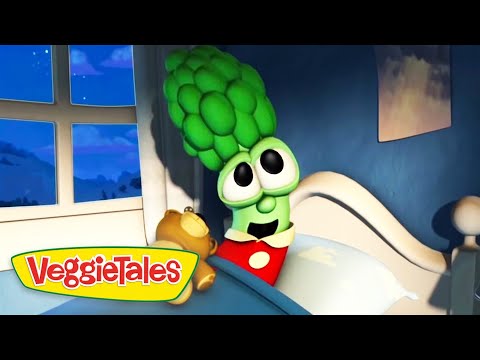 Green broccoli character in bed with a yellow teddy bear, smiling at the viewer; VeggieTales logo appears in the bottom-left corner.