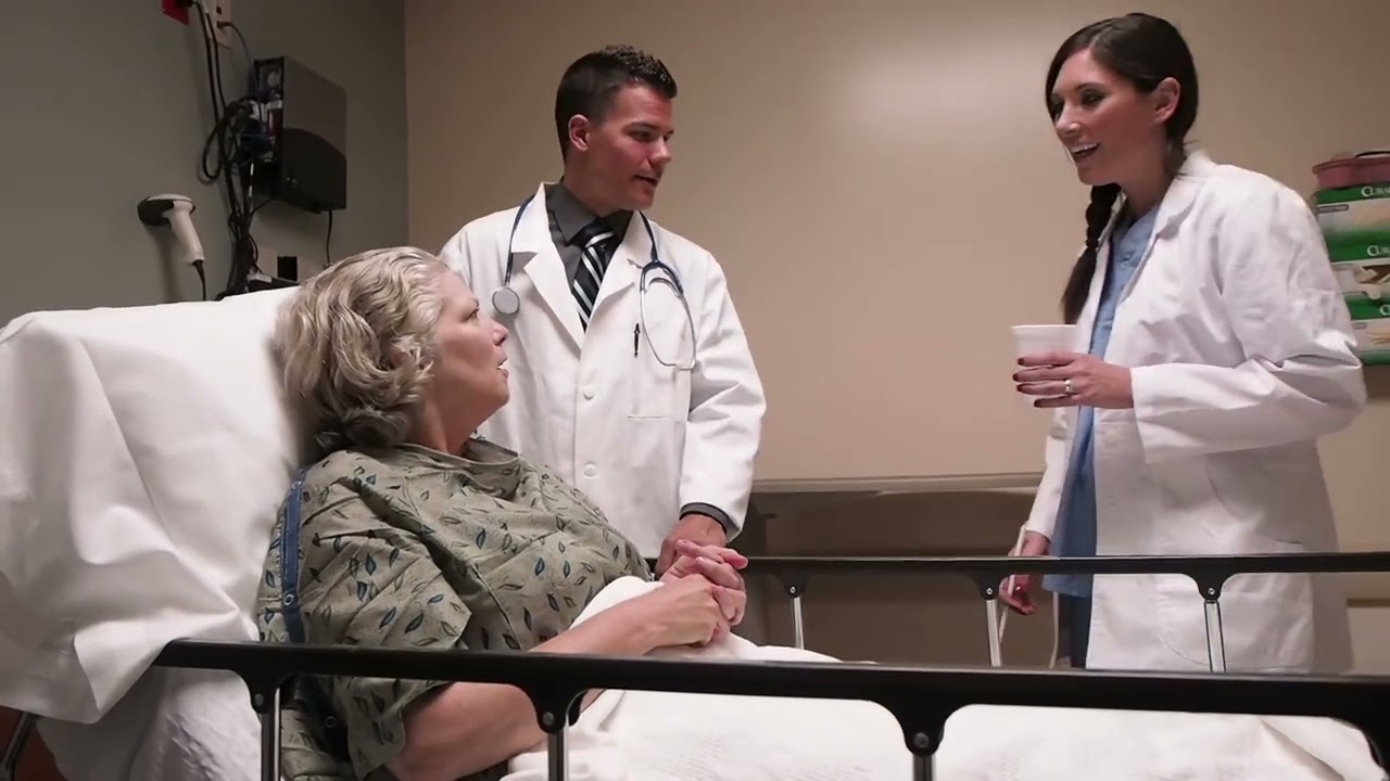 Woman in a hospital bed speaking with two doctors