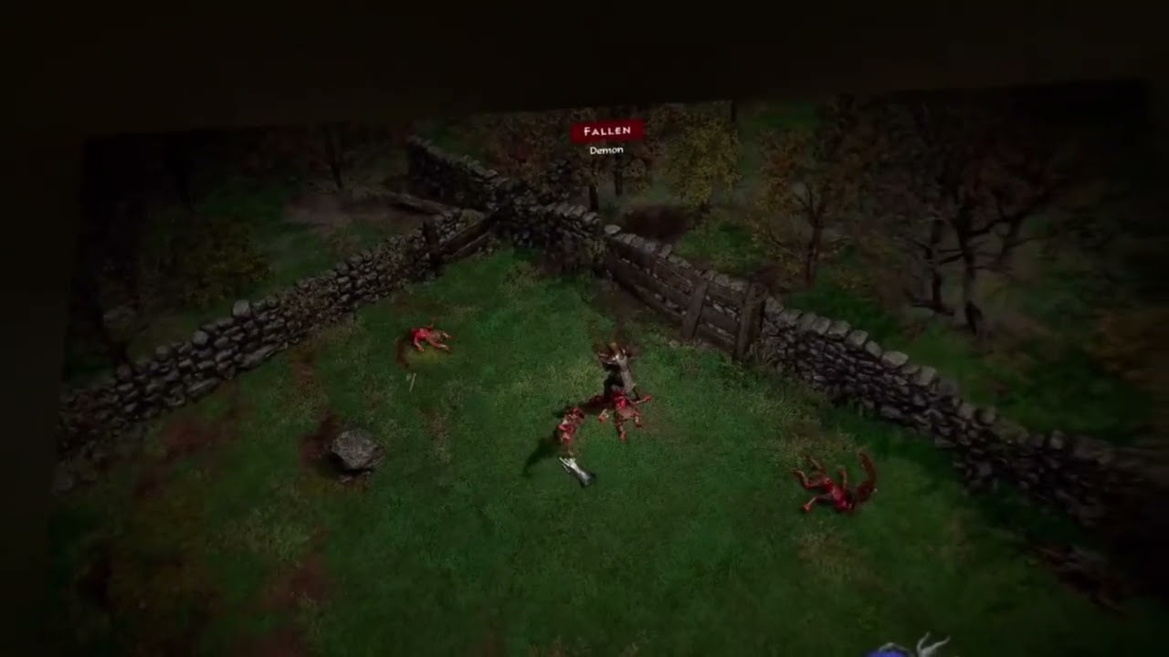 Diablo II: Resurrected's classic overhead view in VR: a Fallen demon beside a low stone wall on a dark grass field