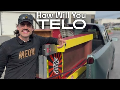 Joey the Cat standing beside the TELO electric truck with a skeeball machine loaded in the bed, from TELO Trucks