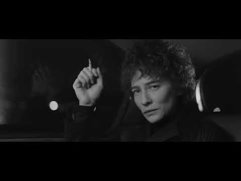 Trailer frame: black-and-white Jude Quinn (Cate Blanchett) under harsh lights, mic stand jutting forward