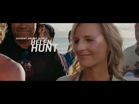 Trailer overhead: a lone surfer drops into a clean face — echoed by score cues like 'Back in the Water'