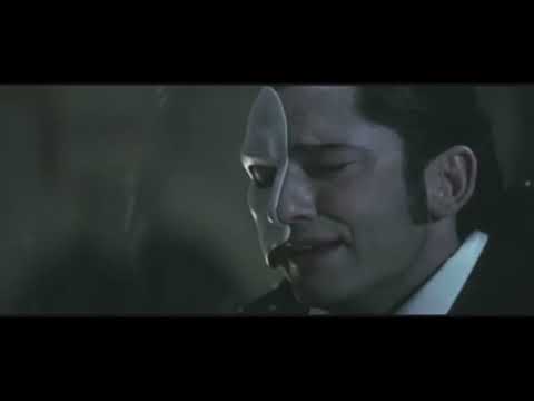 The Phantom of the Opera (2004) trailer still — chandelier glow, velvet proscenium, and masked silhouette