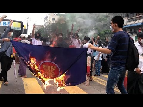 شاهد متظاهرون يحرقون علم رابطة دول جنوب شرق آسيا مع بدء محاكمة أون سان سو تشي…