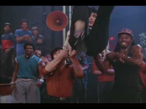 Trailer montage: night club performance with mirror lights and shoulder-padded crowd