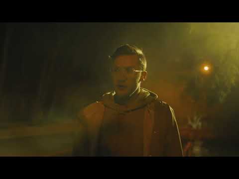 A man with glasses standing on a street at night.