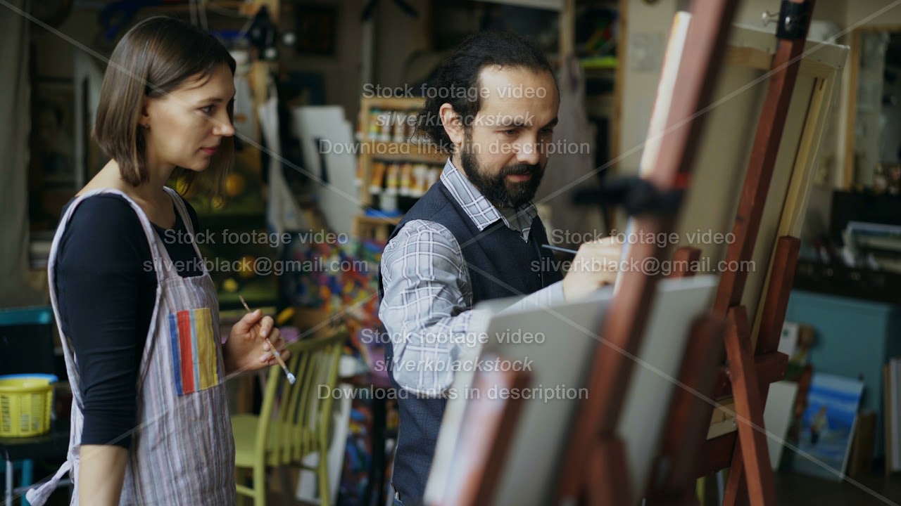 Skilled artist teacher showing and discussing basics of painting to student at art-class