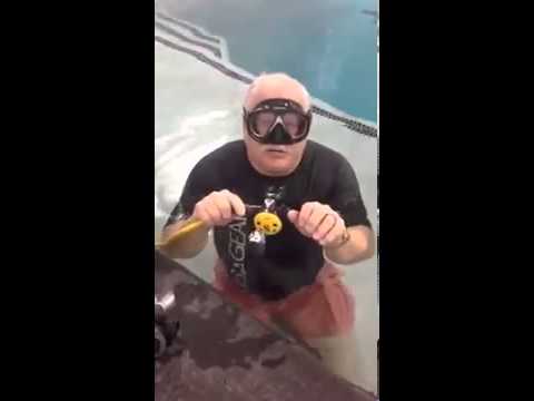 How do I clear my regulator from water while scuba diving?