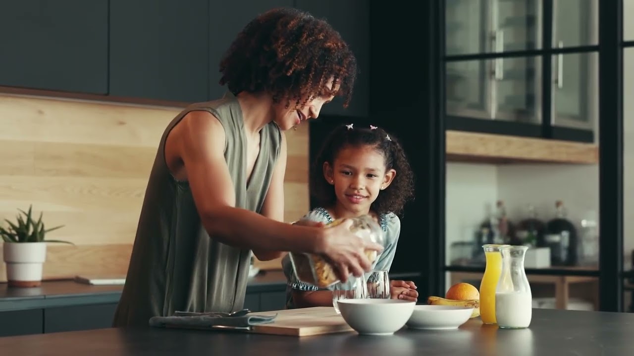 Parent helping a child prepare food in the kitchen