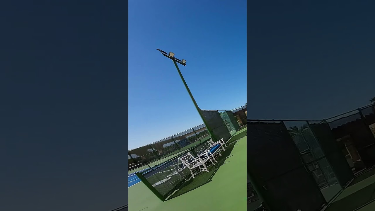 Drone view climbing above an outdoor pickleball court in the sun