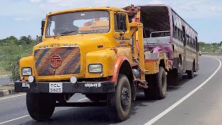 Old TATA tow truck in action towing a big city bus.