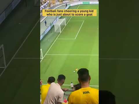 Football fans cheering a young kid who is just about to score a goal.