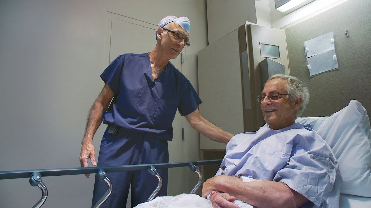 Patient in hospital bed with doctor standing beside him
