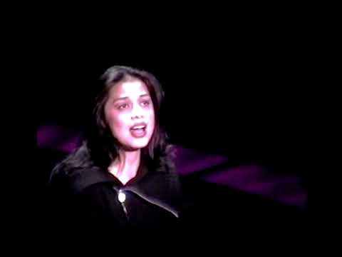 Close-up of a soloist at mic with projected text during the Lennon musical’s confessional section