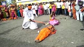 Blindfolded axeman cracks open coconuts held by three women