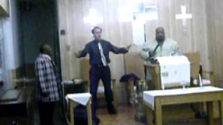 White preacher shouting while Tyrone Bellamy plays the organ
