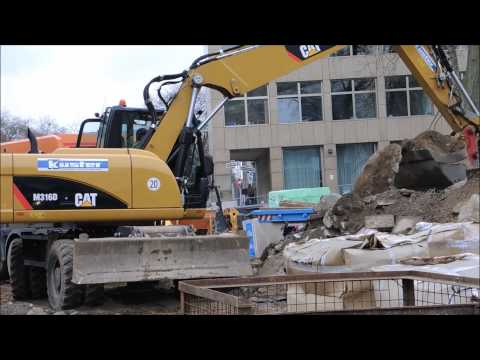 Bagger Caterpillar M316D verlädt Beton auf LKW
