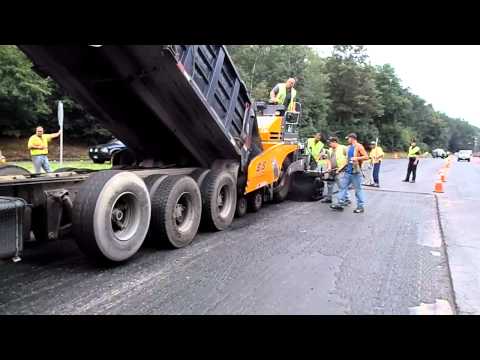 Dump truck feeding asphalt into the paver as the paver pushes the truck