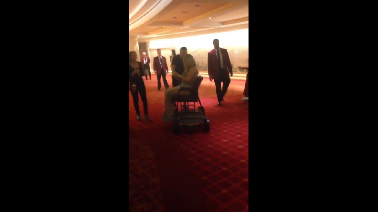 Mariah Carey gets escorted to the stage while being pushed by a bodyguard in a customized chair thumnail