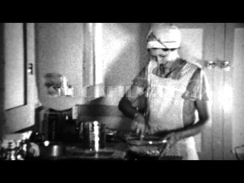 1936: Aproned women cooking in kitchen sifting flour for biscuits. DENVER, COLORADO