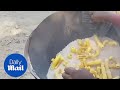 A man cooks raw potato snacks using hot sand - Daily Mail