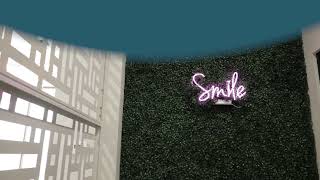 Wall with texture of green bush with stylized text saying smile