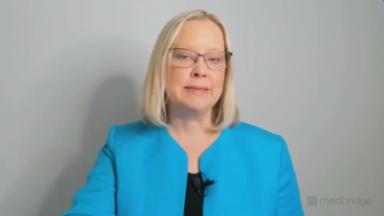 A blonde woman in glasses and a turquoise blazer speaks about digital healthcare for medbridge.