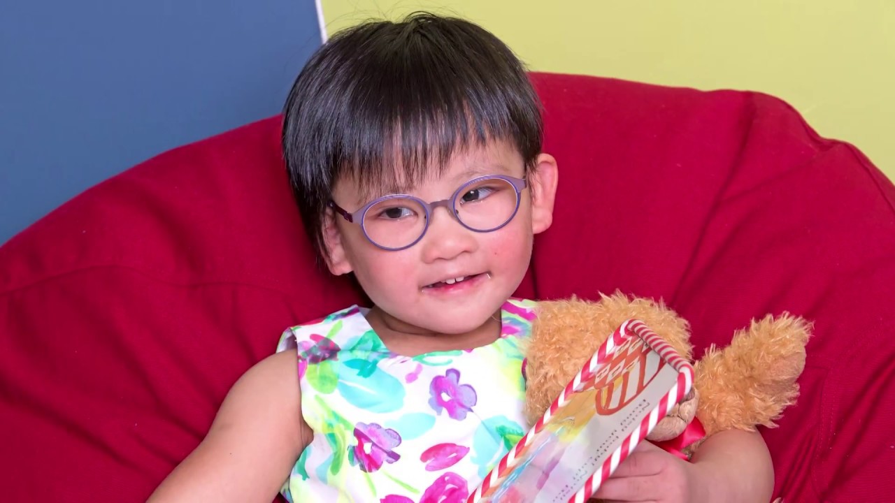 Vivien in a red bean bag chair with her teddy bear and a book