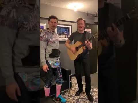 Conan and Flula singing and playing guitar from the backstage of Conan and friends tour