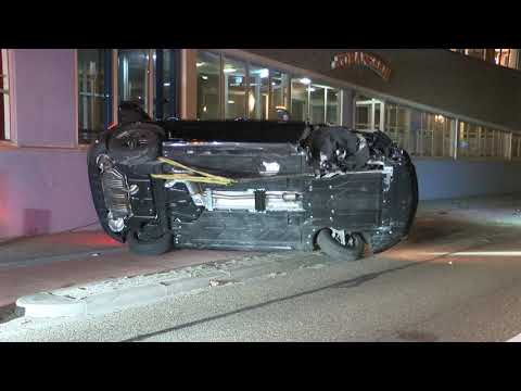 Auto slaat over de kop en komt ondersteboven tegen flatgebouw tot stilstand