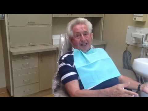 Older man in blue and white striped shirt sitting in dental chair