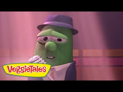 Green veggie character in a suit and hat sings into a microphone on a stage, VeggieTales logo in the corner.