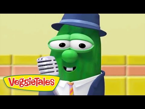 Green VeggieTales bean character wearing a blue hat and suit, smiling while singing into a vintage microphone on a colorful stage. Logo reads VeggieTales.