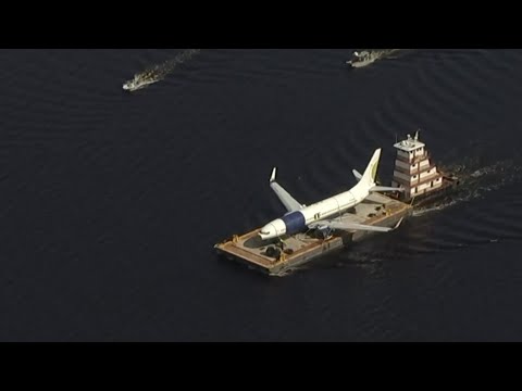 A barge and a crane are moving the Miami Air International plane that ran off a runway and into a river at a Florida military base on Saturday. (May 8)
