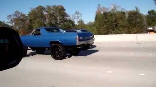 Car with big ass wheels going down the freeway