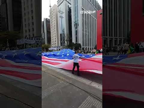 Manifestantes bolsonaristas estendem bandeira dos EUA em ato pró-anistia na Av. Paulista, em SP