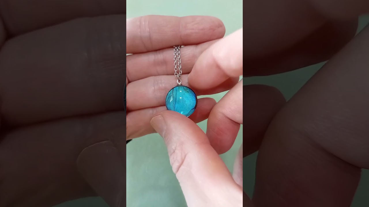 Collana autentica da 18mm con vera ala di Morpho deidamia sotto lente in vetro che mostra una radiosa iridescenza blu marmorizzata