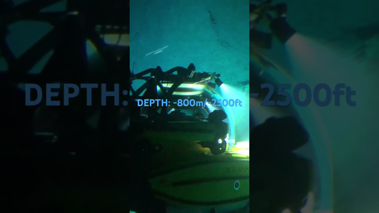 3-person manned submersibles passing each other along the vertical face of a deep ocean mound.