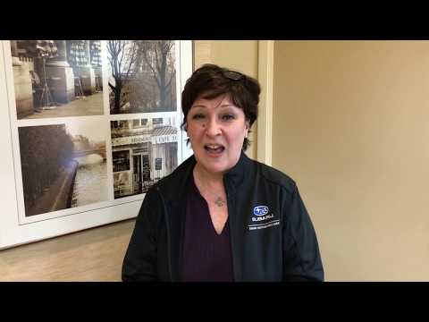 Woman in purple shirt and black jacket standing in dental office