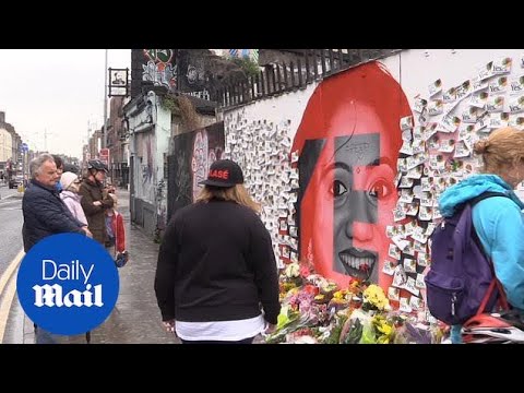 People lay flowers and messages at a mural of Savita Halappanava